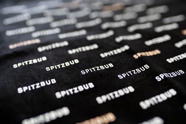 Dieses Bild zeigt das Spitzbub-Logo auf schwarzem Stoff